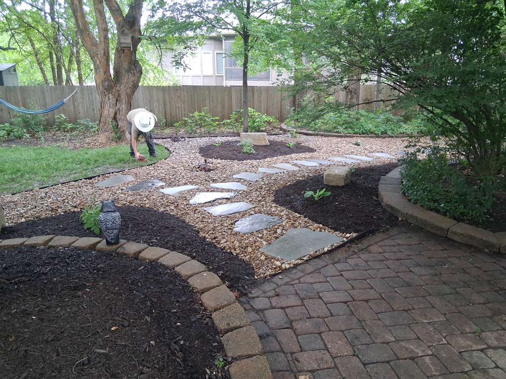 Backyard stepping stone walkway with rock and mulch beds