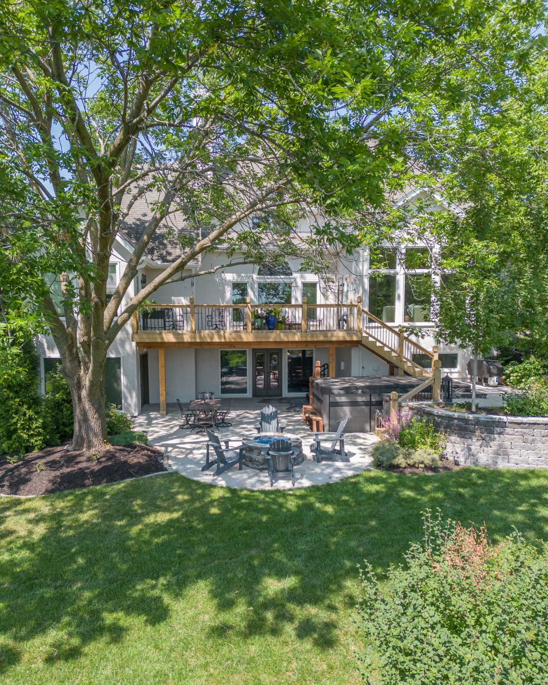Backyard deck with patio furniture, fire pit and lush green lawn