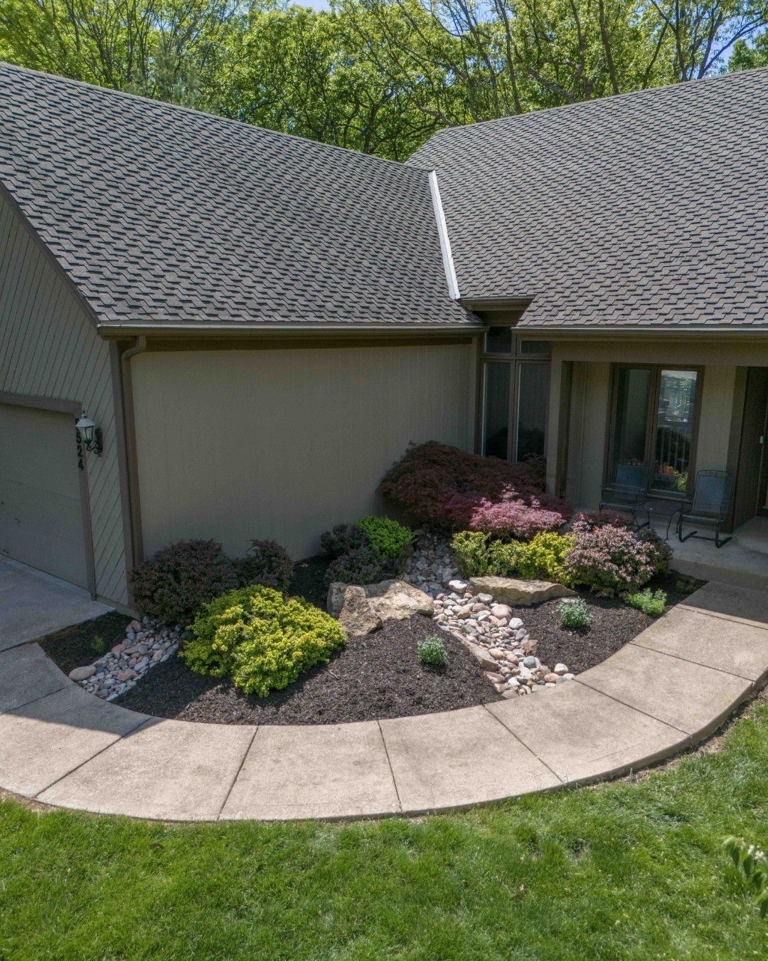 Front yard with curved concrete walkway, rocks and colorful shrubs