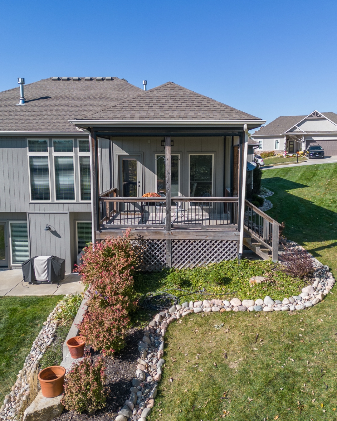 Backyard with rock bed, flowering shrubs and wooden deck