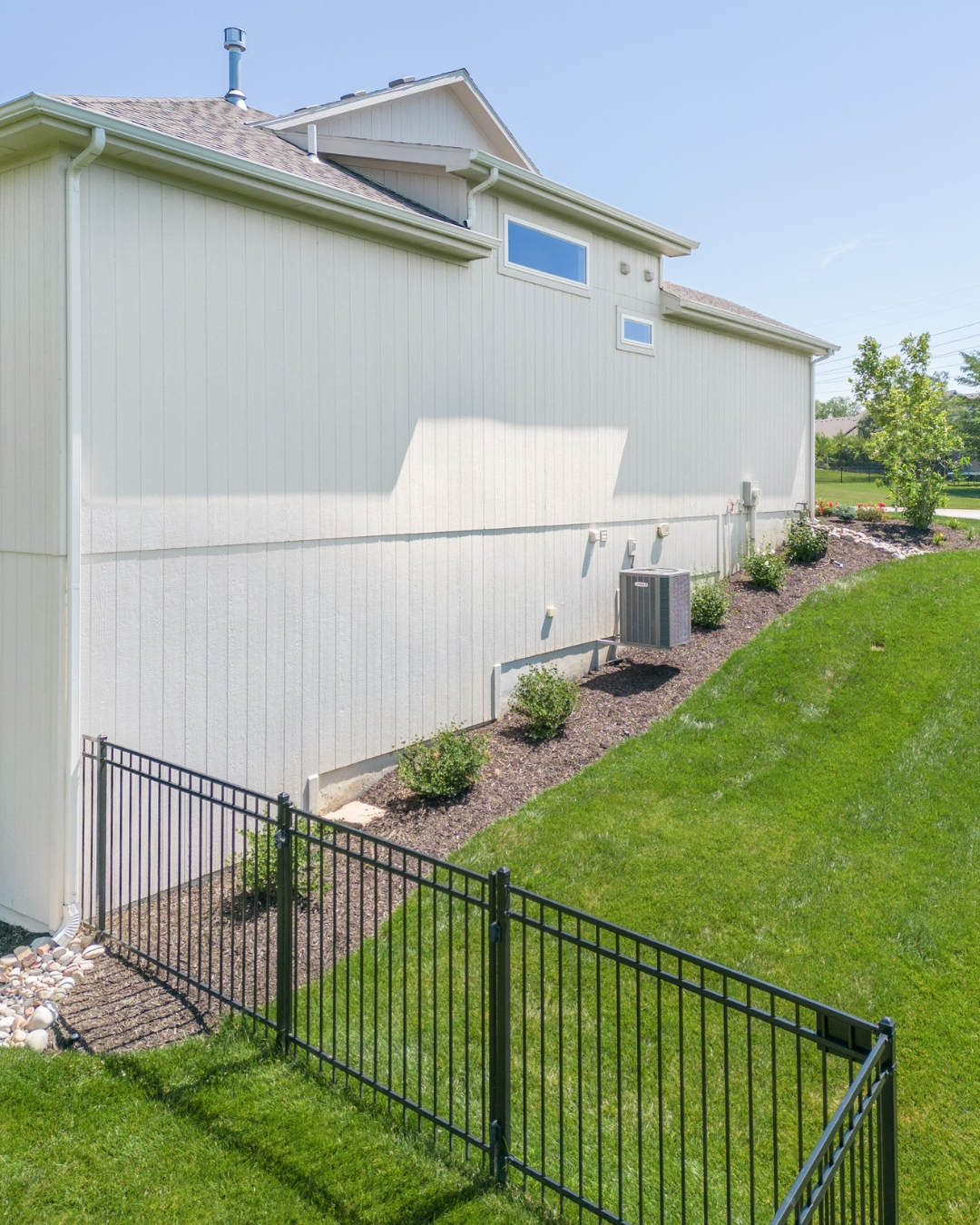 Side yard with black fence, mulch bed and green lawn