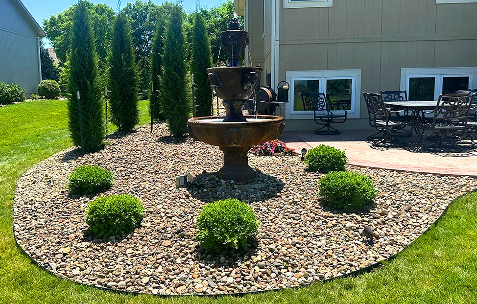 River rock bed with tiered fountain, boxwoods and evergreens